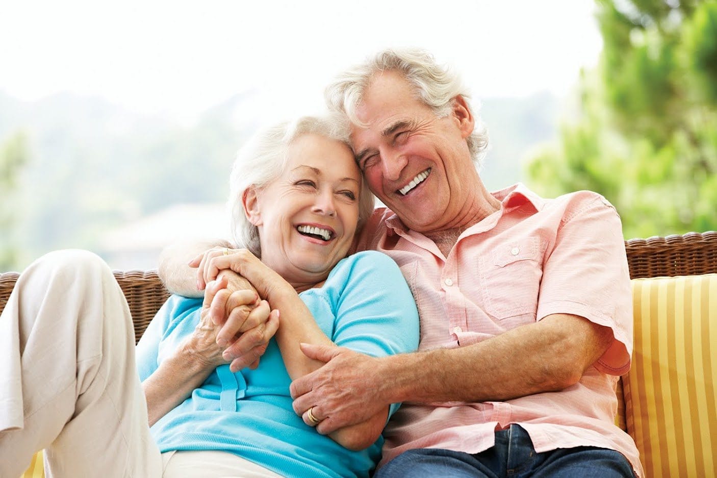 An older couple laughing together on a garden sofa