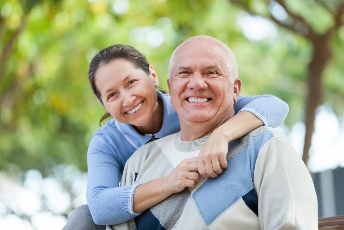 A smiling older couple hugging in a park