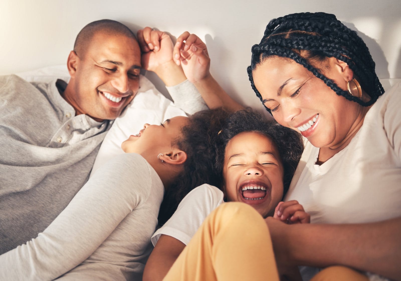 A family of four laughing together in bed