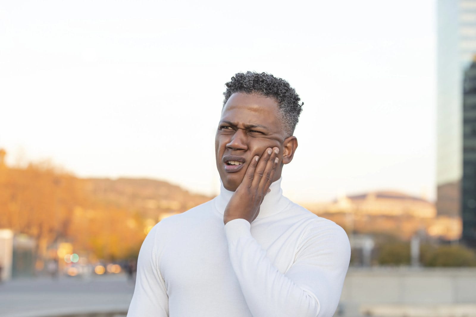 A man outdoors holding his jaw
