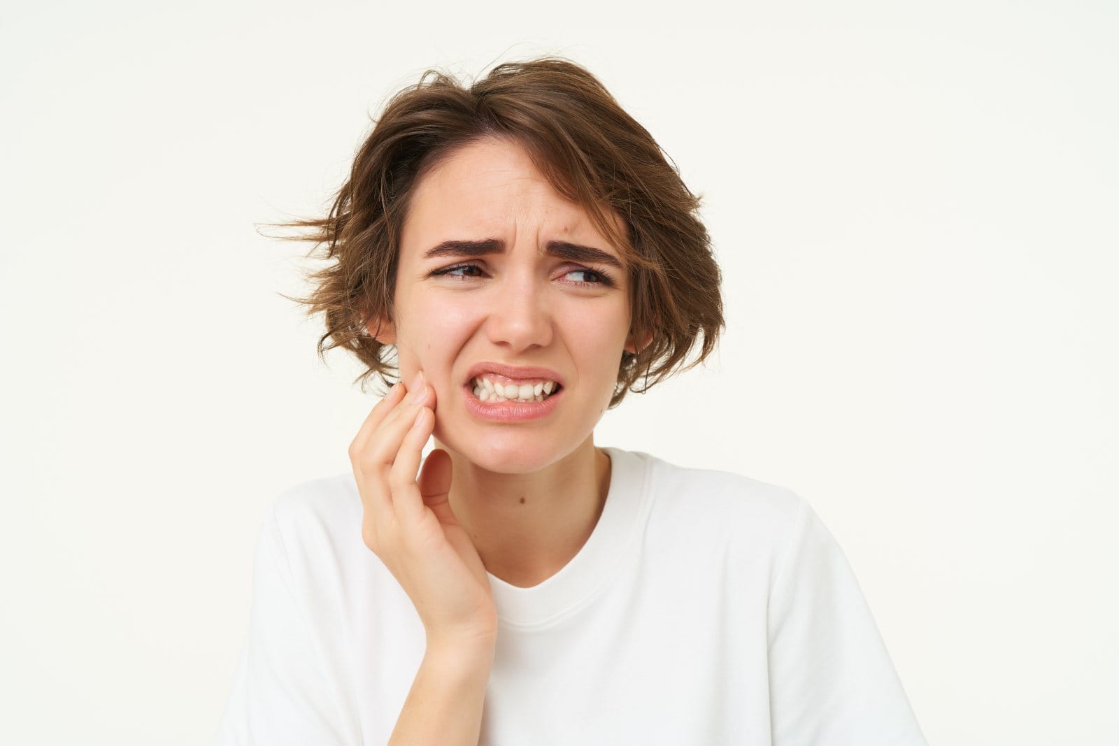 A young woman touching her cheek and wincing