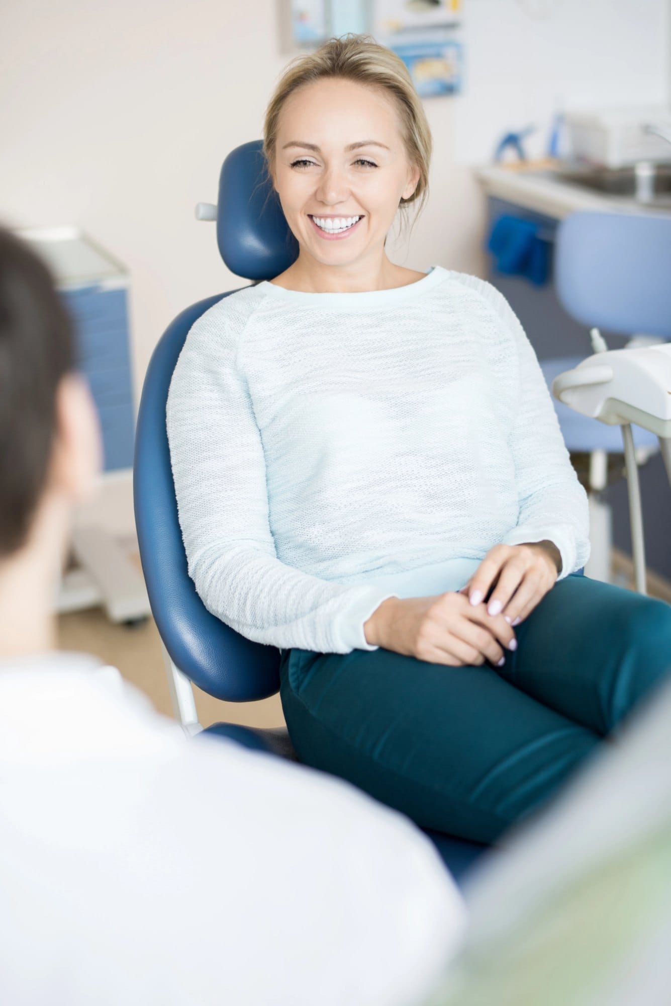 A smiling woman seated in a dental chair during a visit