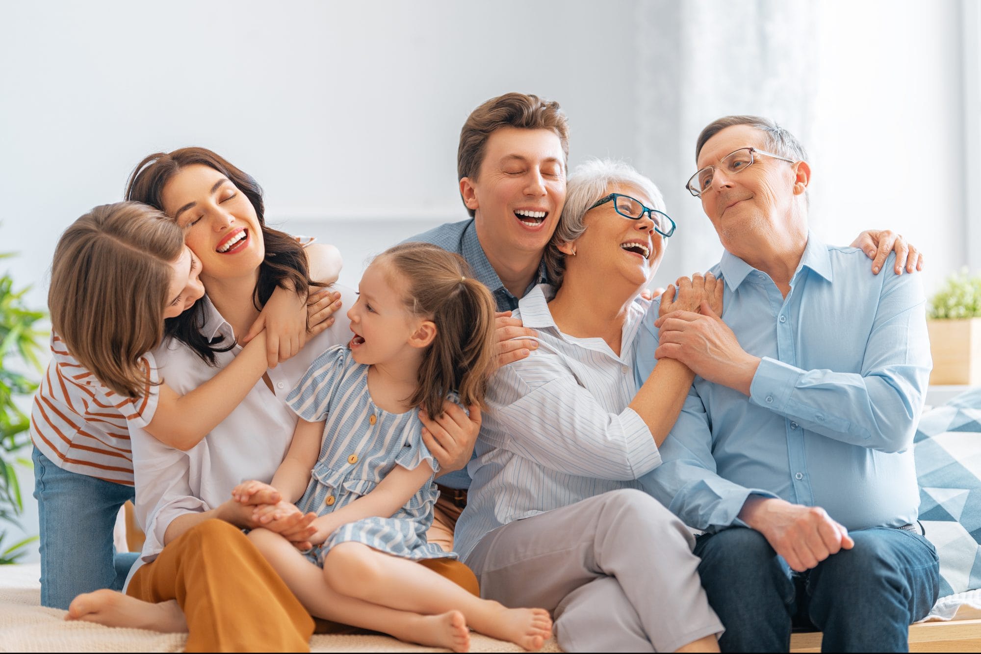 Three generations of a family laughing and hugging together on a sofa
