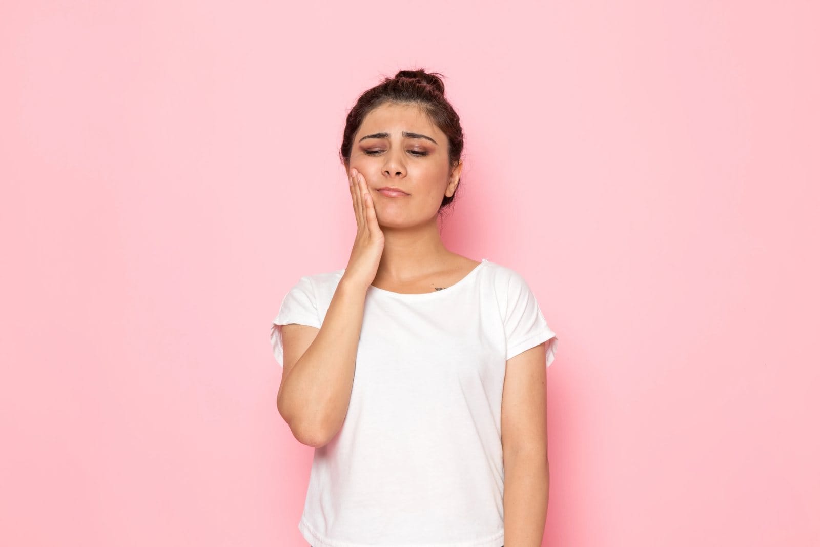 A young woman holding her cheek in discomfort